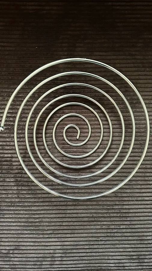 A silver spiral resting on dark ribbed fabric