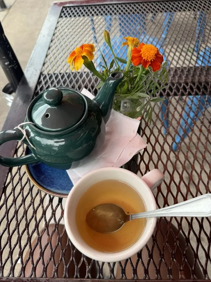 A cup of tea and orange flowers on a garden table